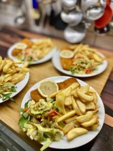Fisch'n Chips mit Salat und Zitrone auf einem Teller.