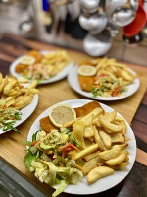 Fisch'n Chips mit Salat und Zitrone auf einem Teller.
