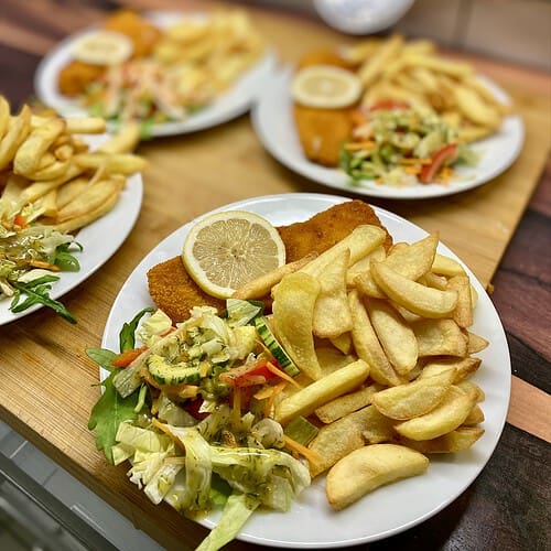 Fisch'n Chips mit Salat und Zitrone auf einem Teller.